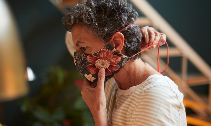 woman adjusts cloth face mask to make it more comfortable 682x408