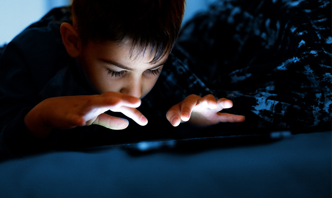 boy looking at an electronic device in the dark