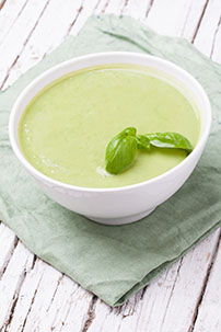cool pea and avocado soup in white bowl on grey napkin 489482953