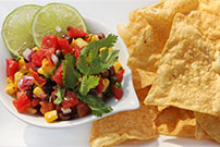 colorful fiesta corn salad in white bowl with side of tortilla chips  185264069
