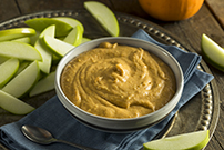 pumpkin dip in grey bowl with slices of granny smith apples next to it 611186822