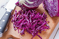 red cabbage cut up on wooden board with knife_467882530
