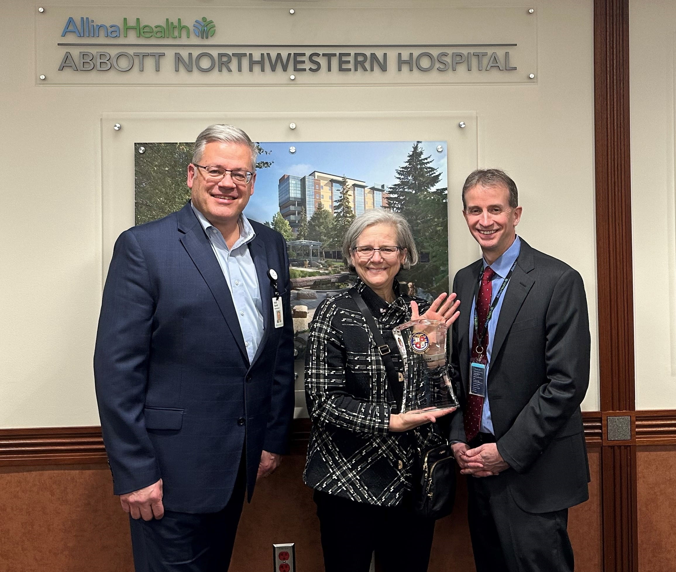 Three people posing with an award (two men and one woman).