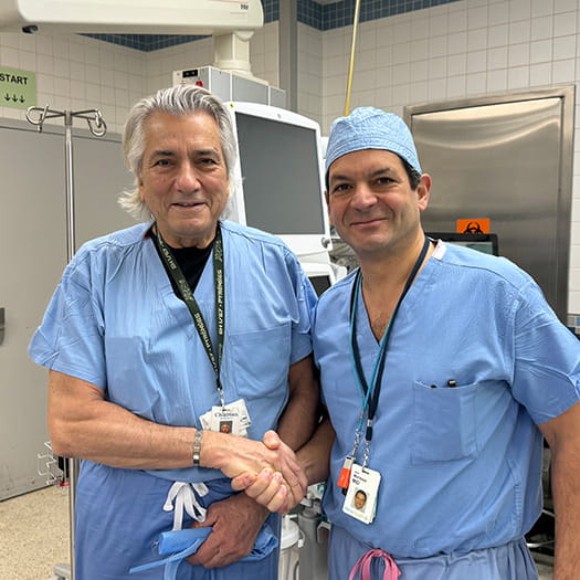 Dr. Kayan in surgical clothes looking at scans with a colleague