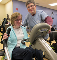 a ckri volunteer helps a woman on an exercise bike