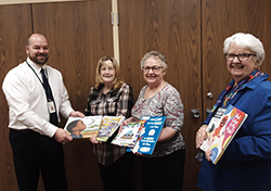 A group of people from the Faribault Auxiliary pose with books
