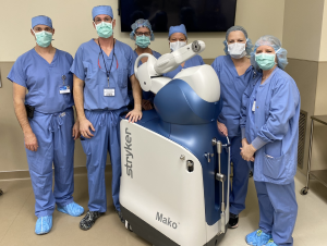 A surgical team posing with a mako surgical robot.