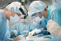 a surgeon performs surgery in an operating room surrounded by surgical team members