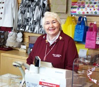 A Unity volunteer stands smiling behind the cash register in the Unity gift shop