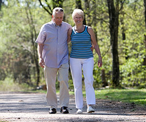 older couple walking in wooded area