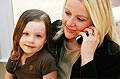 woman on phone with daughter in her lap