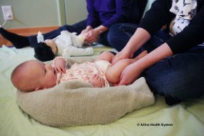 Baby lies on back while leg is massaged.