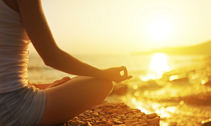 person meditating on beach to alleviate daily stress