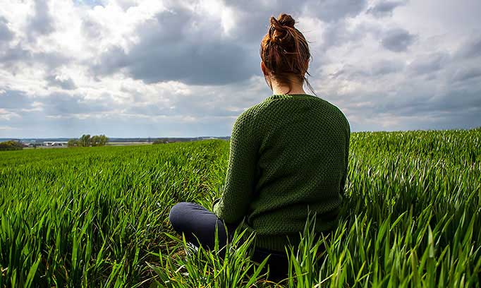 woman sitting in field, relaxing to beat heart disease