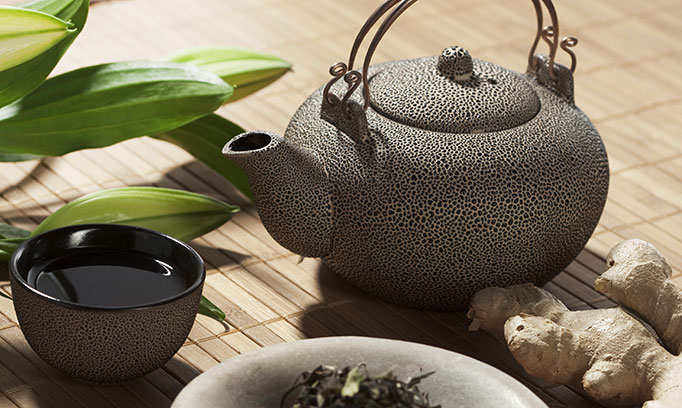Teapot, lily buds, tea bowl, and ginger root placed on a bamboo floor