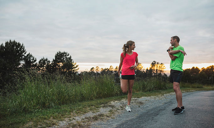 couple stretching before a run, exercising in pairs may help you stick with an exercise plan