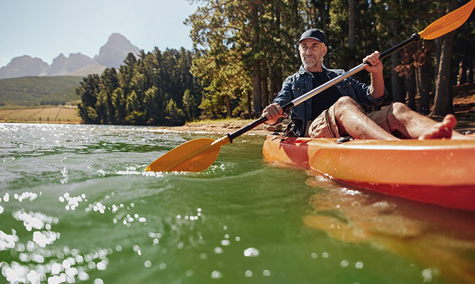 A healthy, fit older man kayaks in a secluded wilderness