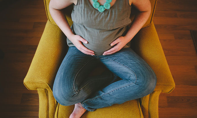 woman in a chair cradling her pregnant belly and her top 5 pregnancy questions