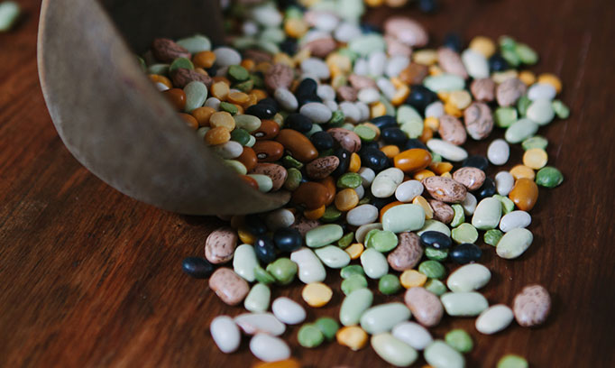 A tipped over bowl spilling out various types of beans