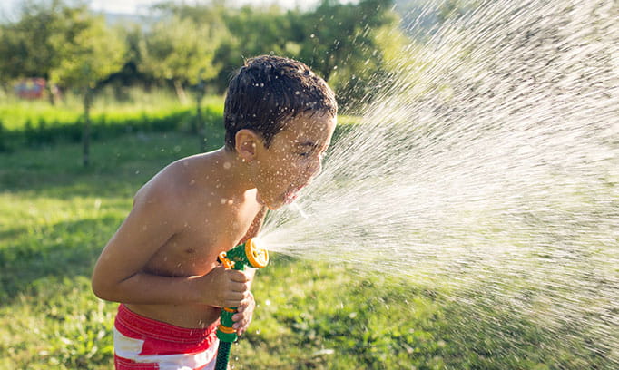 young boy drinks from garden house to prevent dehydration