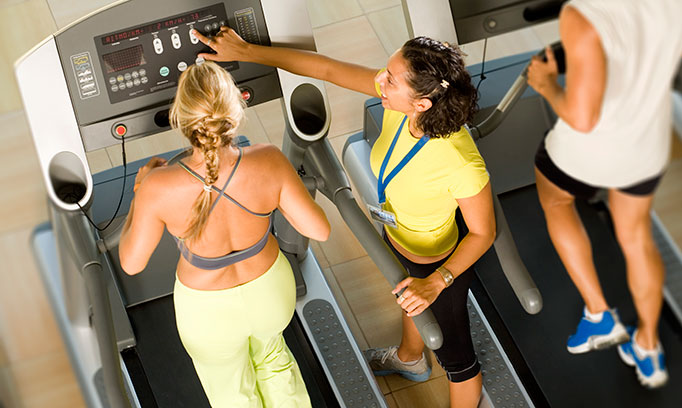 Trainer coaching a woman on a treadmill on how they can increase their running cadence