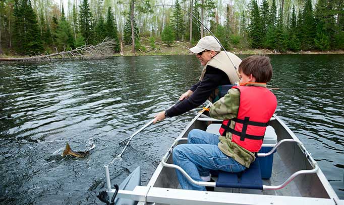 Dad and son fishing and wearing life jackets for safety