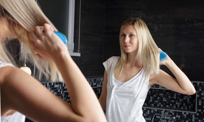 Woman styling her hair at mirror