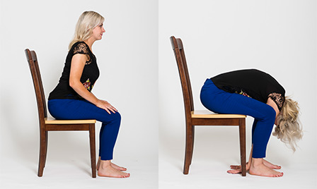 A woman performing the forward fold chair yoga pose