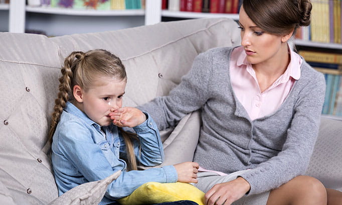 An anxious young girl is comforted by her mom