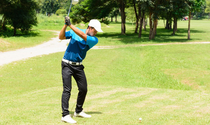 Golfer prepares to swing club after stretches to prevent back injury 