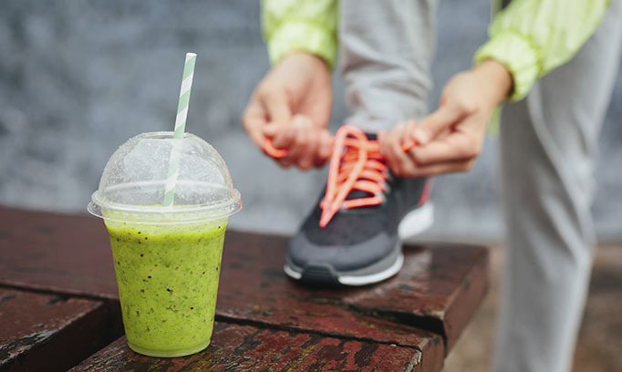 Woman with pre-workout smoothie prepares for a run