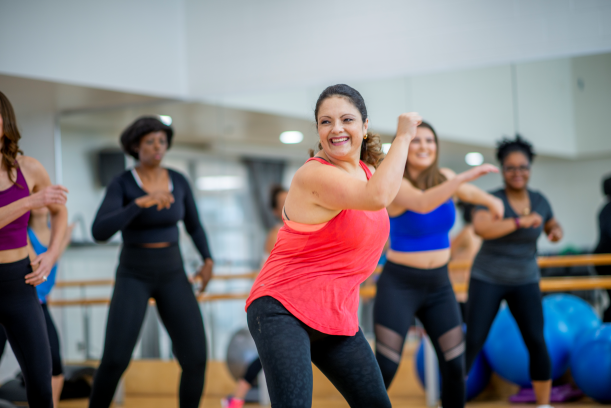 woman with a smile on her face with other women behind her during a fitness class 