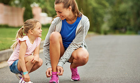 Mother and daughter lacing up tennis shoes