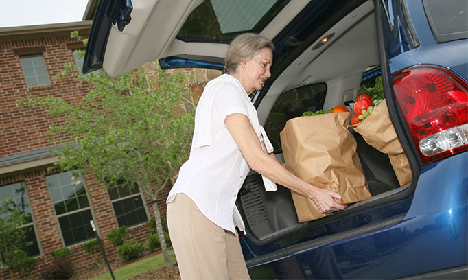 older woman loading groceries into car