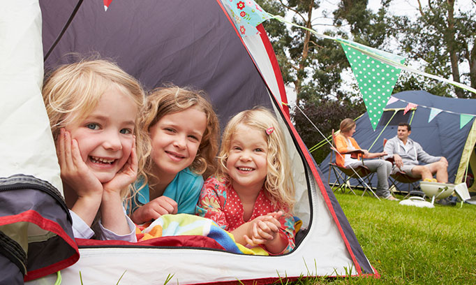 A middle child in a tent with her older and younger sisters