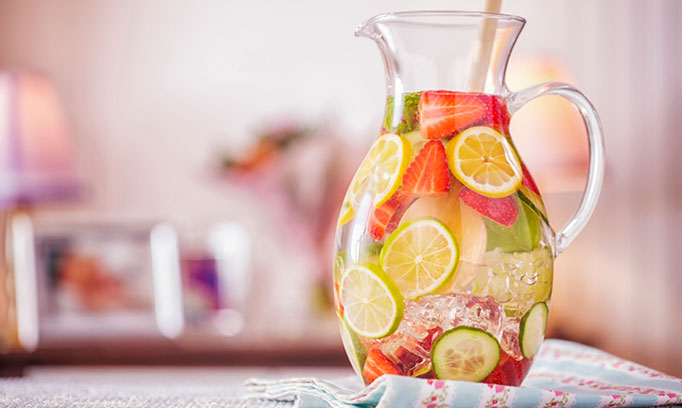 A pitcher of fruit infused water on a table that can help quench thirst