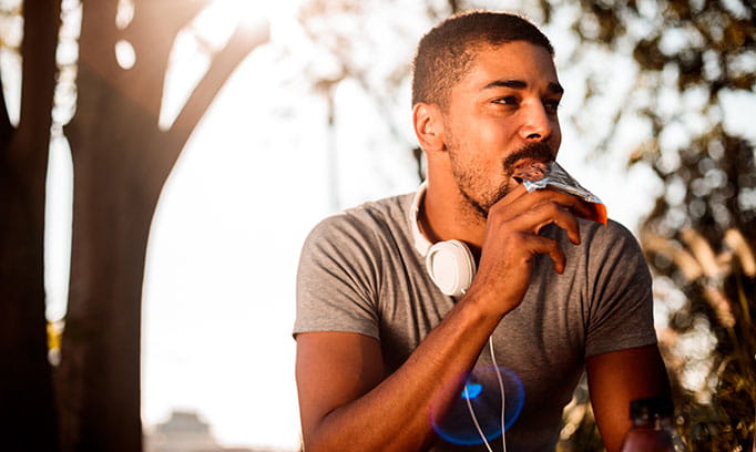 athletic man eats meal replacement bar for weight loss
