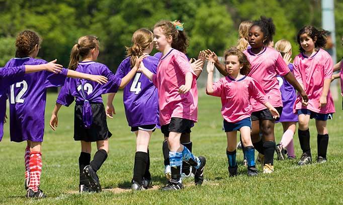 Youth soccer teams high-five each other after a game