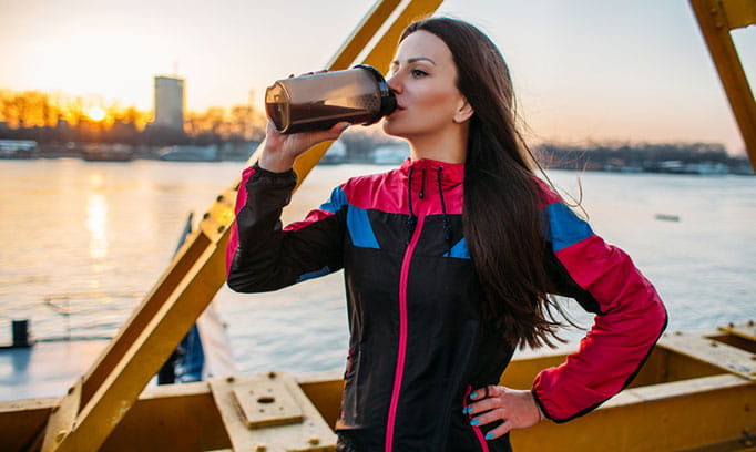 woman shown drinking dark beverage similar to activated charcoal mixture