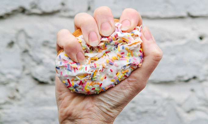 Close up of a donut being squeezed in a hand.