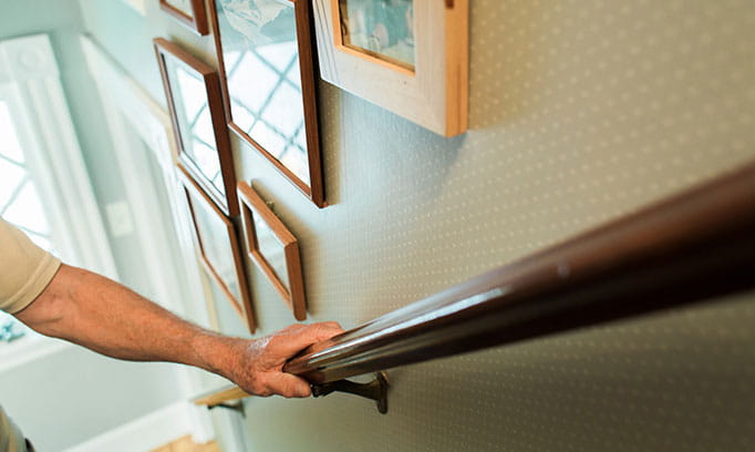 adult walking upstairs holding railing to prevent falls