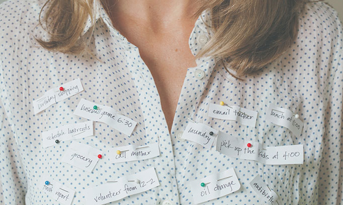 Woman with many notes pinned to her blouse to symbolize having too much to do