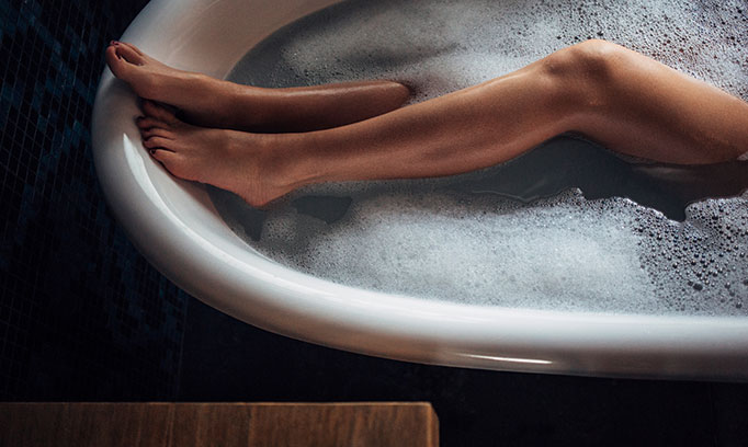 woman's bar legs soaking in bath tub while skipping her workout