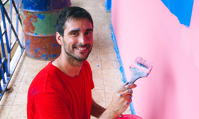Young man helps with painting project as a volunteer