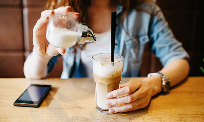 Woman adding sugar to beverage