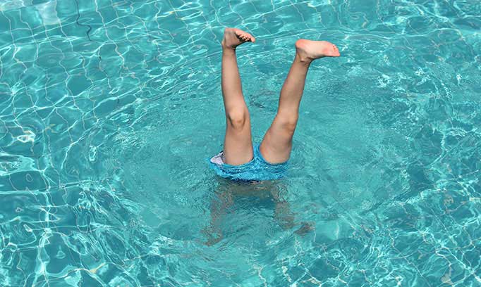 Swimmer dives underwater in pool, which can contribute to swimmer's ear 