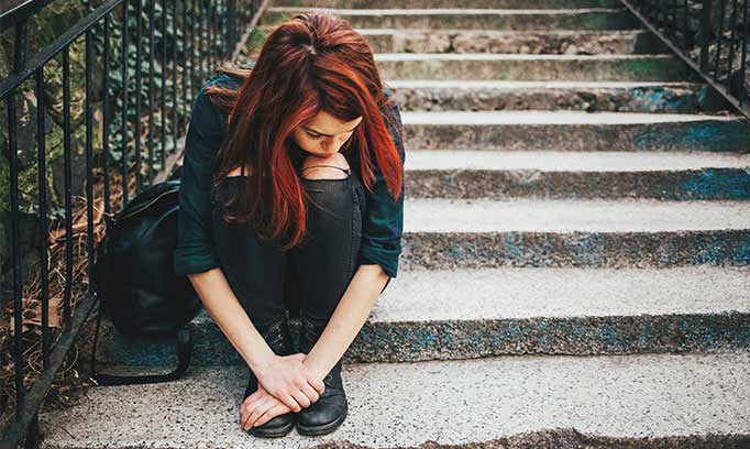 A young girl sits alone while deep in thought