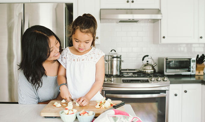 Mom and preschooler enjoy cooking together in kitchen