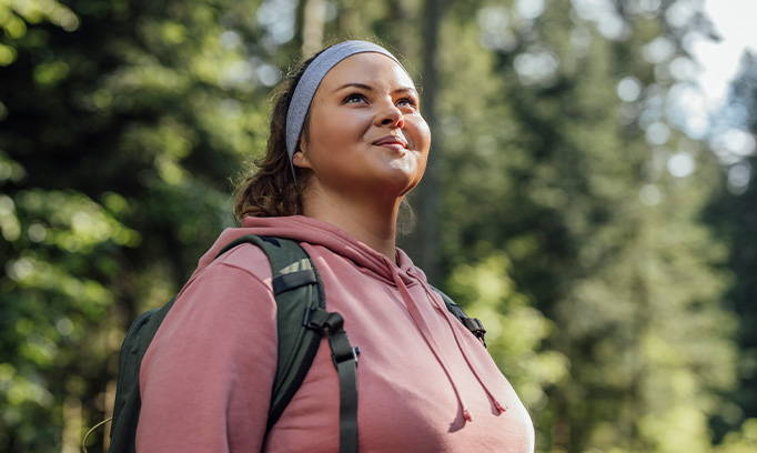 Woman on a hike looking up at the sky smiling because she doesn't have seasonal allergies
