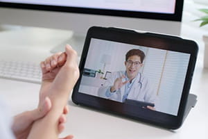 Patient with wrist pain on a virtual video call on a tablet with a doctor.